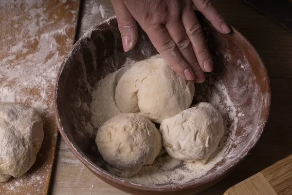 Balls of dough. Plywood cutting board, wooden flour sieve and wo