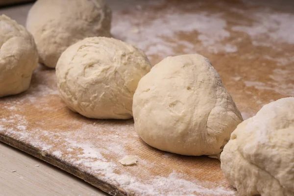 Balls of dough. Plywood cutting board, wooden flour sieve and wo — Stock Photo, Image