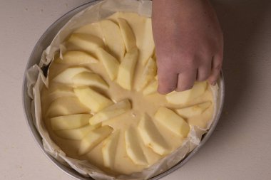 Kadın eli pişirmeden önce pastaya elma dilimleri koyar..