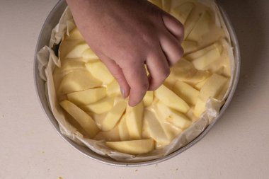 Kadın eli pişirmeden önce pastaya elma dilimleri koyar..