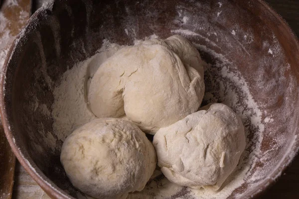 Balls of dough. Plywood cutting board, wooden flour sieve and wooden rolling pin - tools for making dough