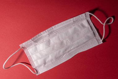 Kırmızı arka planda beyaz tıbbi maske. Yakın plan.