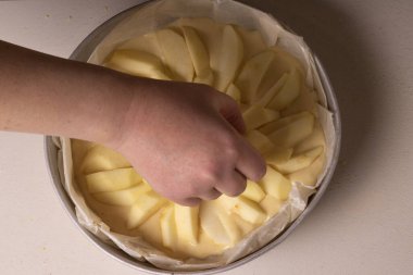 Kadın eli pişirmeden önce pastaya elma dilimleri koyar.