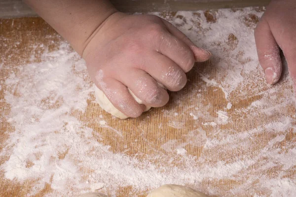 A woman kneads the dough. Plywood cutting board, wooden flour sieve and wooden rolling pin - tools for making dough