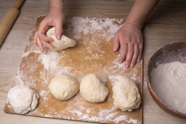 A woman kneads the dough. Plywood cutting board, wooden flour sieve and wooden rolling pin - tools for making dough