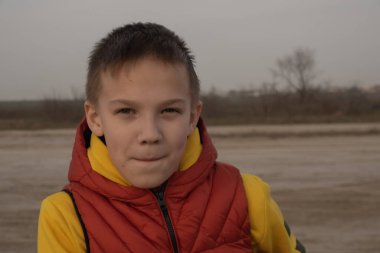 10 yaşında bir çocuk, karantina sırasında boş bir sahilde turuncu bir yelek giyiyor..