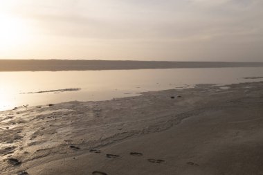 Gün batımından önce kumlu bir sahilde bir adamın izleri.