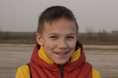 10 yaşında bir çocuk, karantina sırasında boş bir sahilde turuncu bir yelek giyiyor..