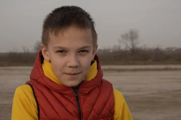 A boy of 10 years in an orange vest on an empty beach during quarantine. — Stock Photo, Image