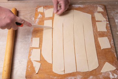 Female hands slices the dough on a cutting board with a white knife. Cooking at home clipart