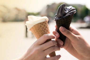 Kadının holding eritme dondurma waffle koni yaz ışık şehir arka plan üzerinde elinde eller. Mutlu tatil kavramı. Fotoğrafı kapatın.