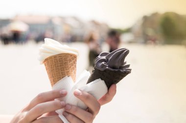 Kadının holding eritme dondurma waffle koni yaz ışık şehir arka plan üzerinde elinde eller. Mutlu tatil kavramı. Fotoğrafı kapatın.