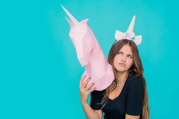 Kawaii tienermeisje. Schattige jonge vrouw met eenhoorn hoorn houden handgemaakt papier roze eenhoorn over blauwe achtergrond. — Stockfoto