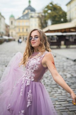 Genç Gil 'in portresi elbise ve menekşe güneş gözlüğü takıyor. kollarında ve yüzünde dövmeler var. Kapatın. Şehir yürüyüşü. Alt kültür özellikleri.