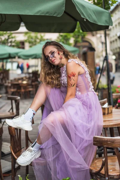 Retrato de gil joven con vestido y zapatillas de deporte y calcetines. tatuajes en sus brazos y cara. De cerca. Paseo por la ciudad . — Foto de Stock