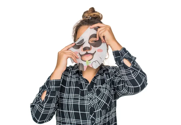 Ung tonåring flicka med ansiktspanda mask tittar på kameran isolerad på vit bakgrund. Kosmetisk procedur. Skönhet spa och kosmetologi. — Stockfoto