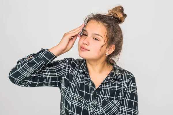 Ung tonåring flicka med ansiktsmask tittar på kameran över vit bakgrund. Kosmetisk procedur. Skönhet spa och kosmetologi. — Stockfoto