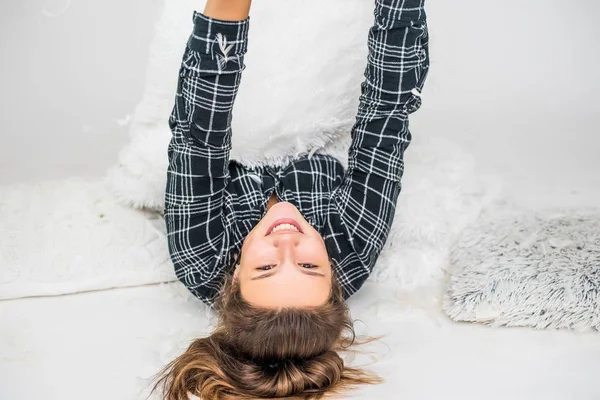 Söt tonåring flicka ha kul på sängen med fjädrar. Bild av ung leende vacker dam ligger i sängen inomhus. — Stockfoto
