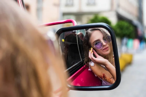 Портрет молодих гіль в сукні та фіолетових сонцезахисних окулярах. татуювання на руках та обличчі, які спостерігають у дзеркалі автомобіля. Близько. Прогулянка містом. Атрибути субкультури . — стокове фото