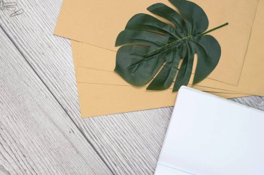 Üst kattaki ofis masasında yatıyordu. Ahşap zemin üzerinde canavar yaprağı olan el işi kağıt mektup..