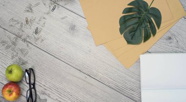 Üst kattaki ofis masasında yatıyordu. Çalışma alanı boş klavye, klavye, ofis malzemeleri, esrar, canavar yaprağı, tahta arka planda gözlük. ofis ürünleri ve kırtasiye çerçeve.