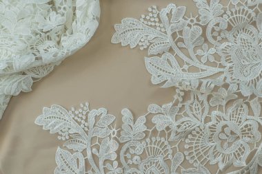 Doku danteli kumaş. Beyaz arka plan stüdyosunda dantel. İplik ya da iplikten yapılmış ince kumaş. Fildişi renkli dantel kumaşın arkaplan resmi. Bej arkaplanda beyaz dantel.