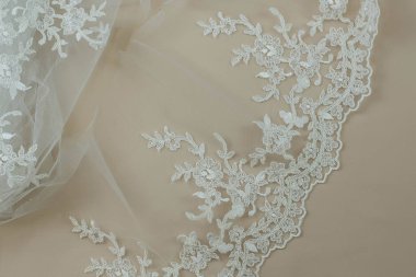 Doku danteli kumaş. Beyaz arka plan stüdyosunda dantel. İplik ya da iplikten yapılmış ince kumaş. Fildişi renkli dantel kumaşın arkaplan resmi. Bej arkaplanda beyaz dantel.