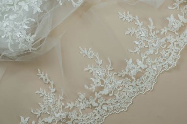 Doku danteli kumaş. Beyaz arka plan stüdyosunda dantel. İplik ya da iplikten yapılmış ince kumaş. Fildişi renkli dantel kumaşın arkaplan resmi. Bej arkaplanda beyaz dantel.