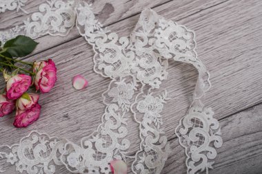 Beyaz ahşap arka plan, beyaz bahar çiçekleri güller ve dantel kurdeleler. Mutlu kadınlar günü. Tahta zemindeki dantelin dokusu.