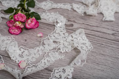 Beyaz ahşap arka plan, beyaz bahar çiçekleri güller ve dantel kurdeleler. Mutlu kadınlar günü. Tahta zemindeki dantelin dokusu.
