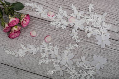 Beyaz ahşap arka plan, beyaz bahar çiçekleri güller ve dantel kurdeleler. Mutlu kadınlar günü. Tahta zemindeki dantelin dokusu.