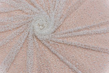 Doku danteli kumaş. Beyaz arka plan stüdyosunda dantel. İplik ya da iplikten yapılmış ince kumaş. Fildişi renkli dantel kumaşın arkaplan resmi. Bej arkaplanda beyaz dantel.