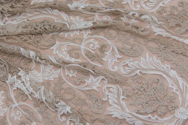 Doku danteli kumaş. Beyaz arka plan stüdyosunda dantel. İplik ya da iplikten yapılmış ince kumaş. Fildişi renkli dantel kumaşın arkaplan resmi. Bej arkaplanda beyaz ve bej dantel.