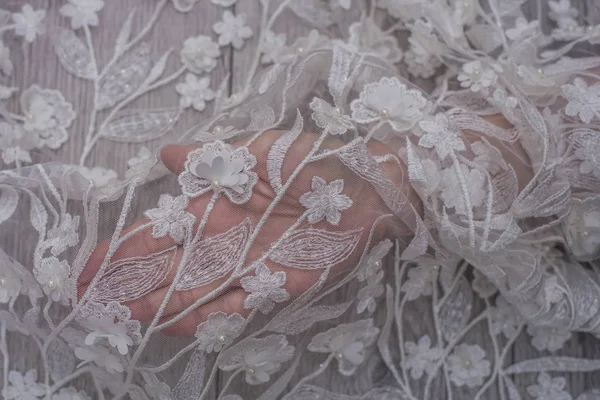 Ручное шитье жемчуга бусин к белой кружевной шелковой ткани, изготовление свадебного платья, украшение с вышивкой — стоковое фото