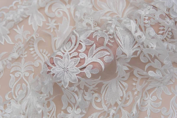A background image of ivory-colored lace cloth. White lace on beige background. — Stock Photo, Image