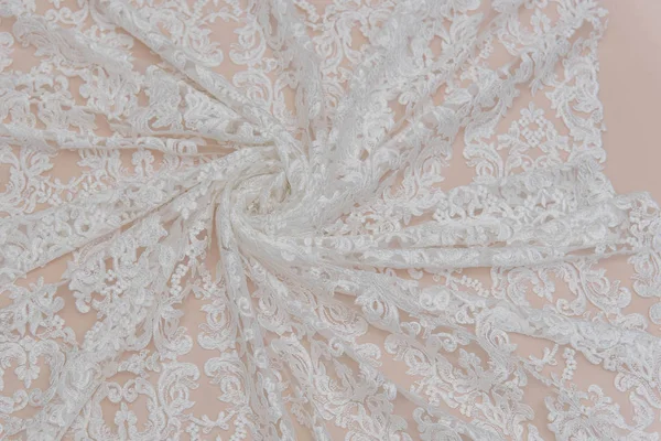 a background image of ivory-colored lace cloth. White lace on beige background.