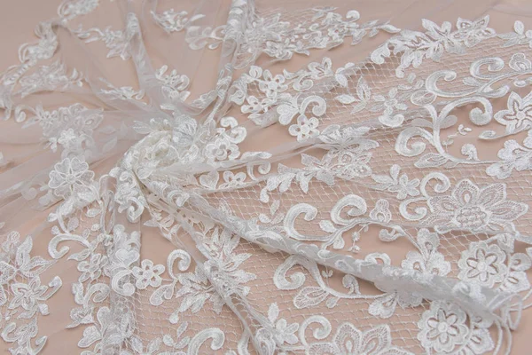 A background image of ivory-colored lace cloth. White lace on beige background. — Stock Photo, Image
