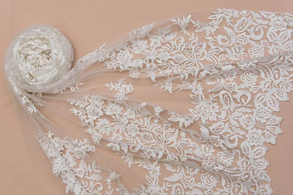 a background image of ivory-colored lace cloth. White lace on beige background.