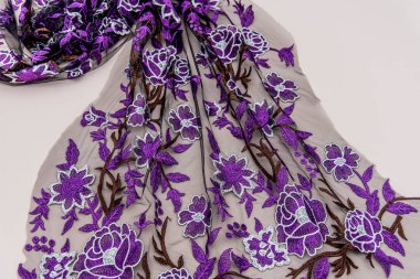 Doku danteli kumaş. Beyaz arka plan stüdyosunda dantel. İplik ya da iplikten yapılmış ince kumaş. Fildişi renkli dantel kumaşın arkaplan resmi. Bej arkaplanda mor dantel.