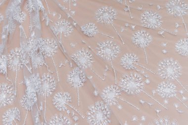 Doku danteli kumaş. Beyaz arka plan stüdyosunda dantel. İplik ya da iplikten yapılmış ince kumaş. Fildişi renkli dantel kumaşın arkaplan resmi. Bej arkaplanda beyaz dantel.