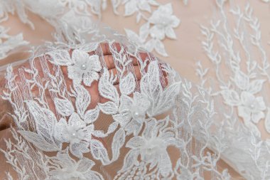 Doku danteli kumaş. Beyaz arka plan stüdyosunda dantel. İplik ya da iplikten yapılmış ince kumaş. Fildişi renkli dantel kumaşın arkaplan resmi. Bej arkaplanda beyaz dantel.