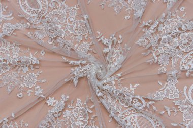 Doku danteli kumaş. Beyaz arka plan stüdyosunda dantel. İplik ya da iplikten yapılmış ince kumaş. Fildişi renkli dantel kumaşın arkaplan resmi. Bej arkaplanda beyaz dantel.