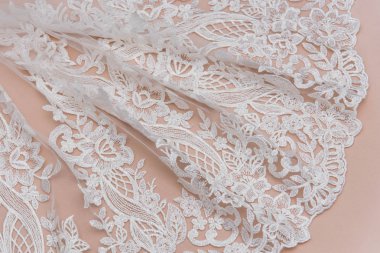 Doku danteli kumaş. Beyaz arka plan stüdyosunda dantel. İplik ya da iplikten yapılmış ince kumaş. Fildişi renkli dantel kumaşın arkaplan resmi. Bej arkaplanda beyaz dantel.