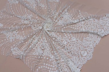 Doku danteli kumaş. Beyaz arka plan stüdyosunda dantel. İplik ya da iplikten yapılmış ince kumaş. Fildişi renkli dantel kumaşın arkaplan resmi. Bej arkaplanda beyaz dantel.