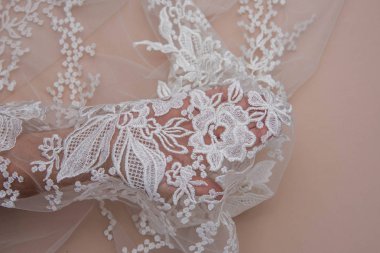 Doku danteli kumaş. Beyaz arka plan stüdyosunda dantel. İplik ya da iplikten yapılmış ince kumaş. Fildişi renkli dantel kumaşın arkaplan resmi. Bej arkaplanda beyaz dantel.