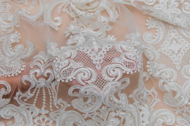 Doku danteli kumaş. Beyaz arka plan stüdyosunda dantel. İplik ya da iplikten yapılmış ince kumaş. Fildişi renkli dantel kumaşın arkaplan resmi. Bej arkaplanda beyaz dantel.