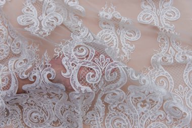 Doku danteli kumaş. Beyaz arka plan stüdyosunda dantel. İplik ya da iplikten yapılmış ince kumaş. Fildişi renkli dantel kumaşın arkaplan resmi. Bej arkaplanda beyaz dantel.