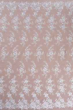 Doku danteli kumaş. Beyaz arka plan stüdyosunda dantel. İplik ya da iplikten yapılmış ince kumaş. Fildişi renkli dantel kumaşın arkaplan resmi. Bej arkaplanda beyaz dantel.