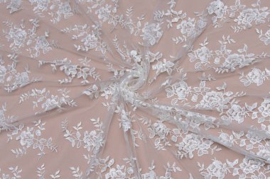 Doku danteli kumaş. Beyaz arka plan stüdyosunda dantel. İplik ya da iplikten yapılmış ince kumaş. Fildişi renkli dantel kumaşın arkaplan resmi. Bej arkaplanda beyaz dantel.