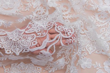 Doku danteli kumaş. Beyaz arka plan stüdyosunda dantel. İplik ya da iplikten yapılmış ince kumaş. Fildişi renkli dantel kumaşın arkaplan resmi. Bej arkaplanda beyaz dantel.